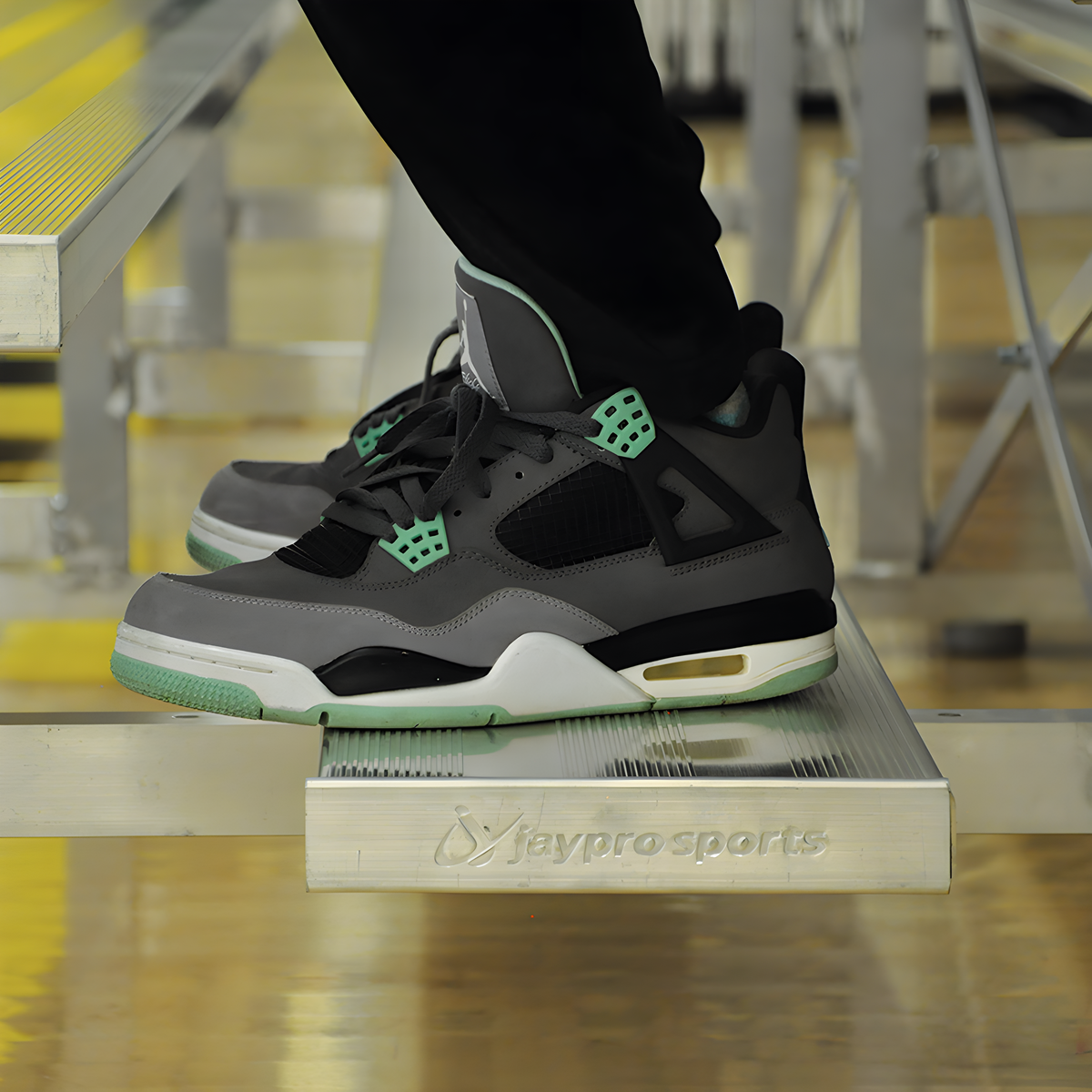 Person wearing sneakers sitting on indoor bleacher seats with aluminum frame