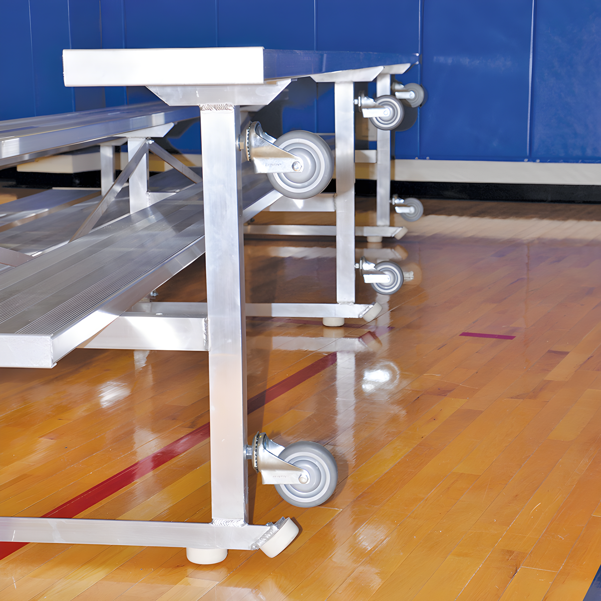 Indoor bleacher seats with aluminum frame and caster wheels on gym floor.