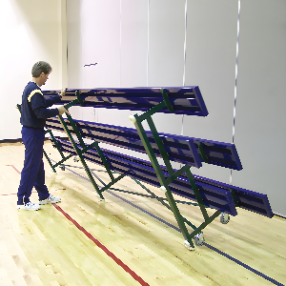 Man folding blue bleachers in gym with championship banners displayed.