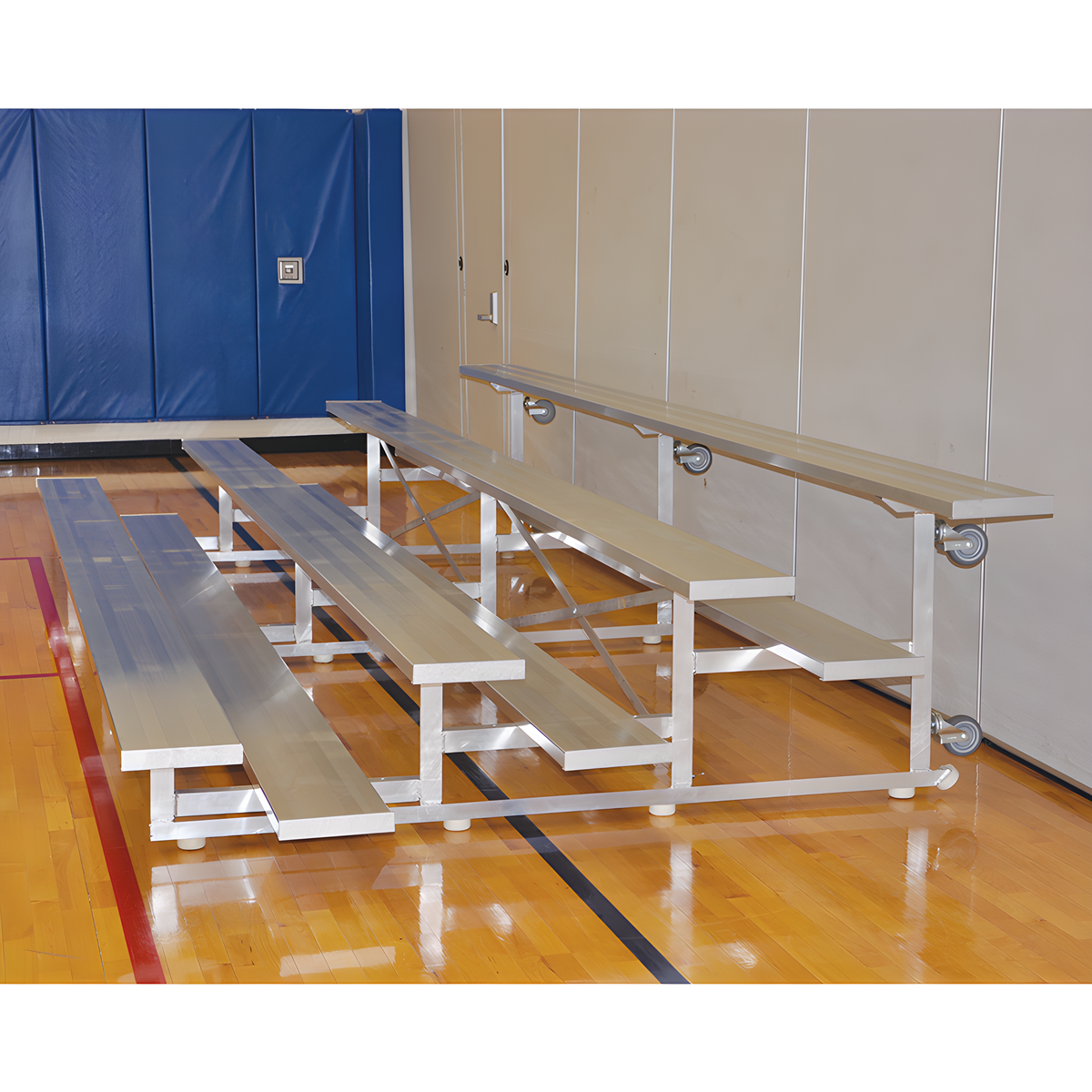 Silver aluminum bleachers with wheels in indoor gymnasium with blue padding.