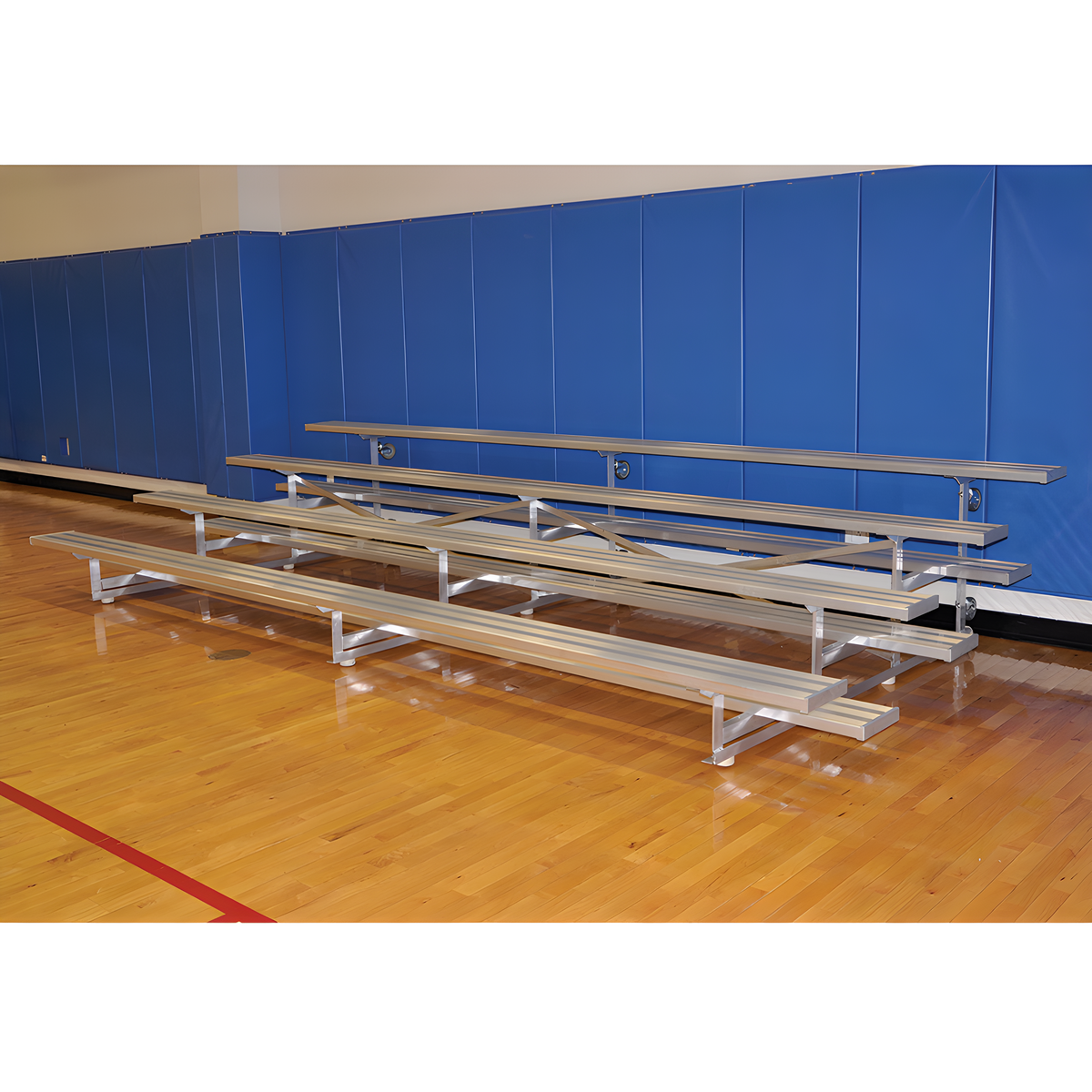 Aluminum bleachers in gymnasium with blue wall padding and flooring.